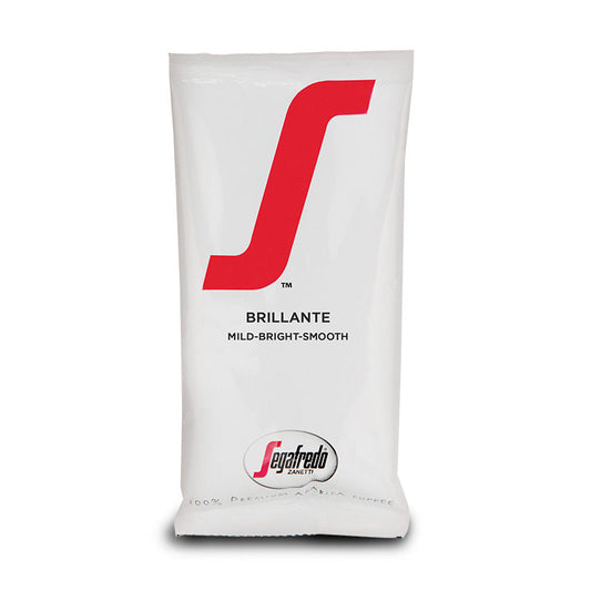 A white coffee bag branded "Segafredo Zanetti" with the word "Brillante" and descriptors "mild-bright-smooth" printed in red and black, featuring lightly roasted Colombian Arabica.