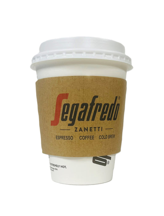 A white to-go coffee cup with a brown Segafredo Branded Cup Sleeves featuring the Segafredo Zanetti logo and text that reads "Espresso Coffee Cold Brew." The cup, available in 12 - 24oz sizes, has a white lid.