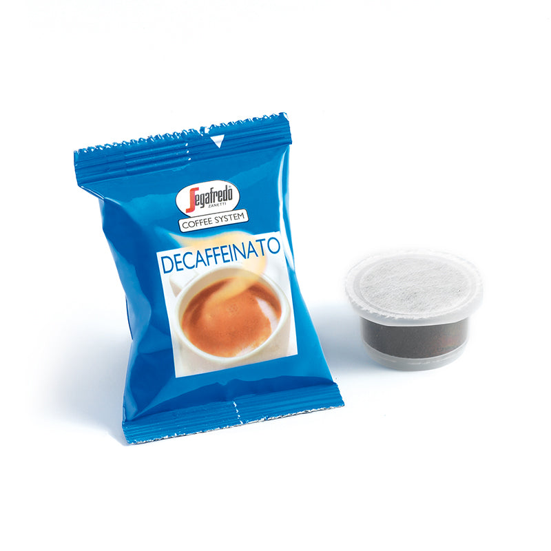 A blue packet labeled "Segafredo Deca Crem (Decaf) Single Serve Espresso Cartridges" next to a single coffee pod on a white background, showcasing Segafredo Zanetti's natural decaffeination process.
